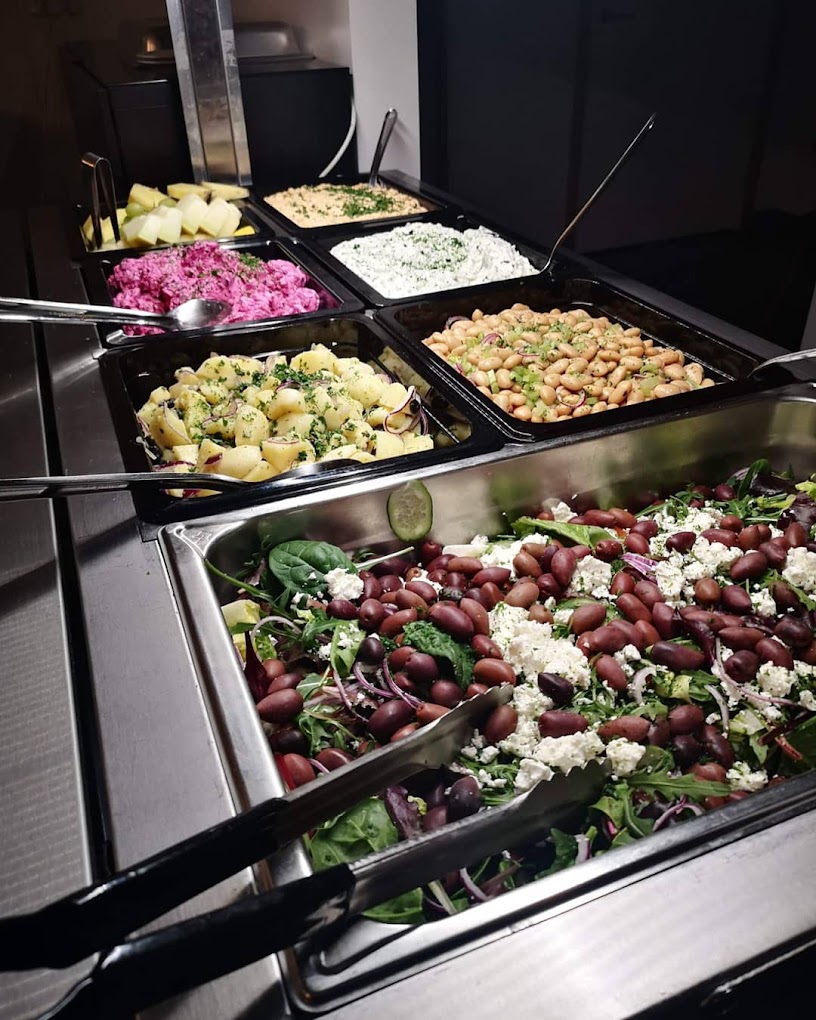 A buffet counter with prepared food and salads.