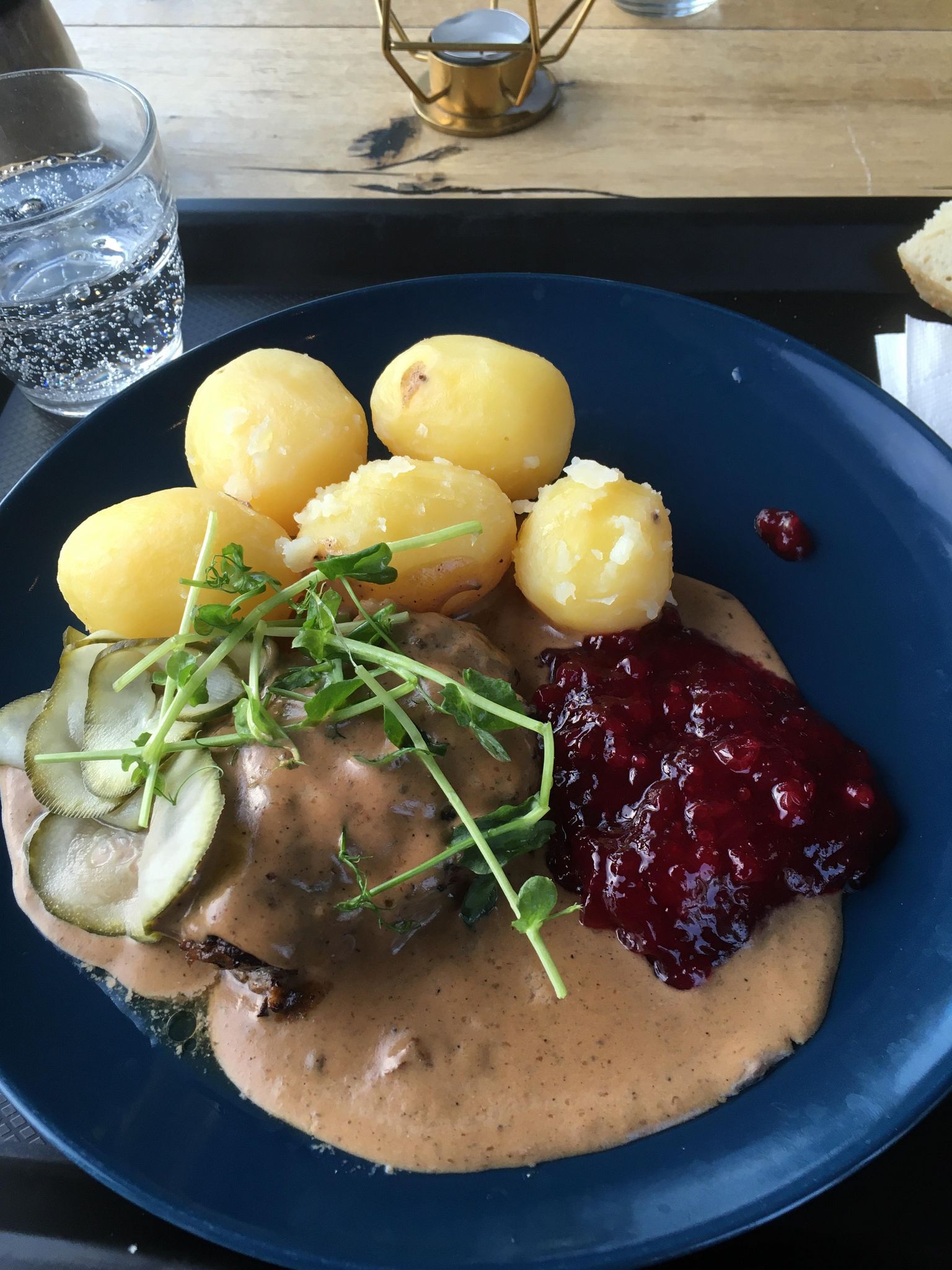 A plated meal with potatoes, sauce and lingonberries.