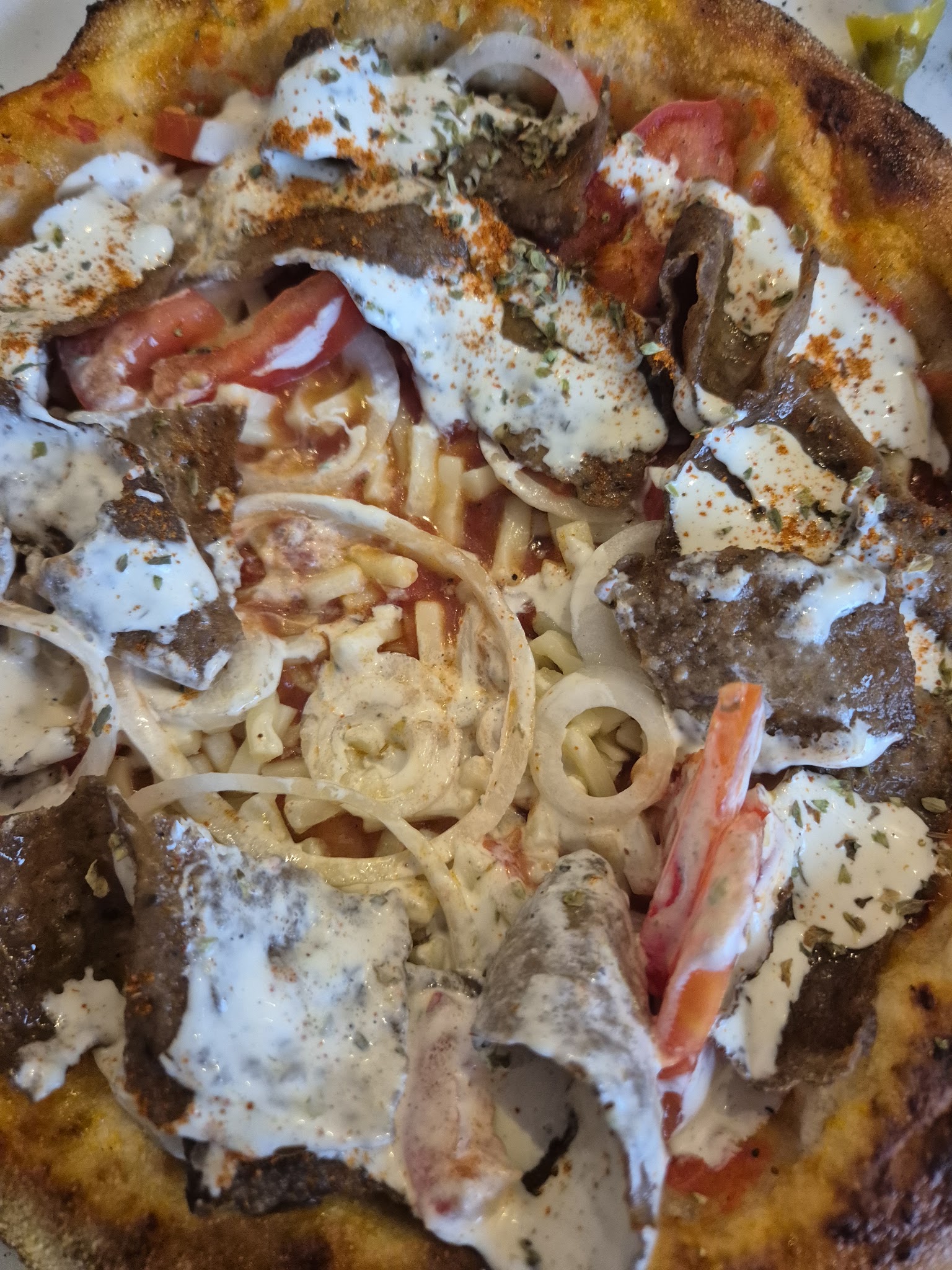 Pizza topped with kebab, onion, tomato and sauce.
